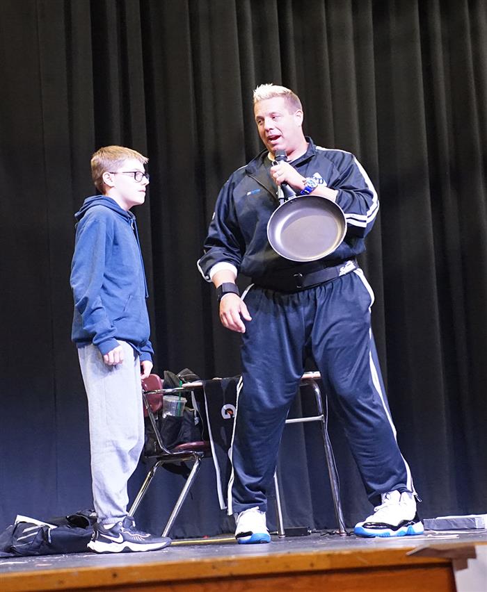 A man and a student stand onstage